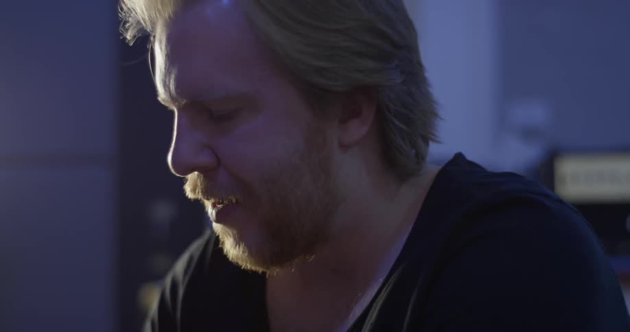 A man smiles and bobs his head as he looks down at something