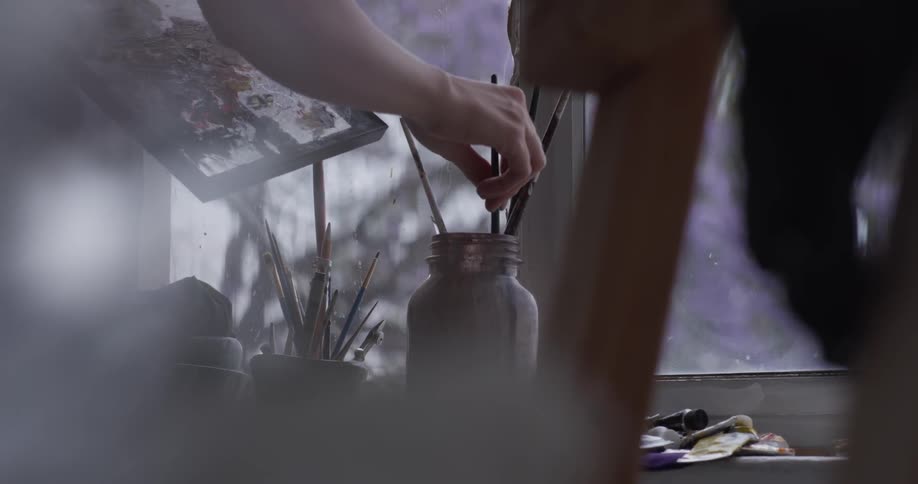 A woman rinsing off a brush in jar of water