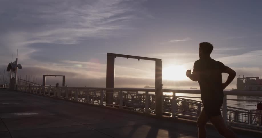 A man running down a pier next to some water