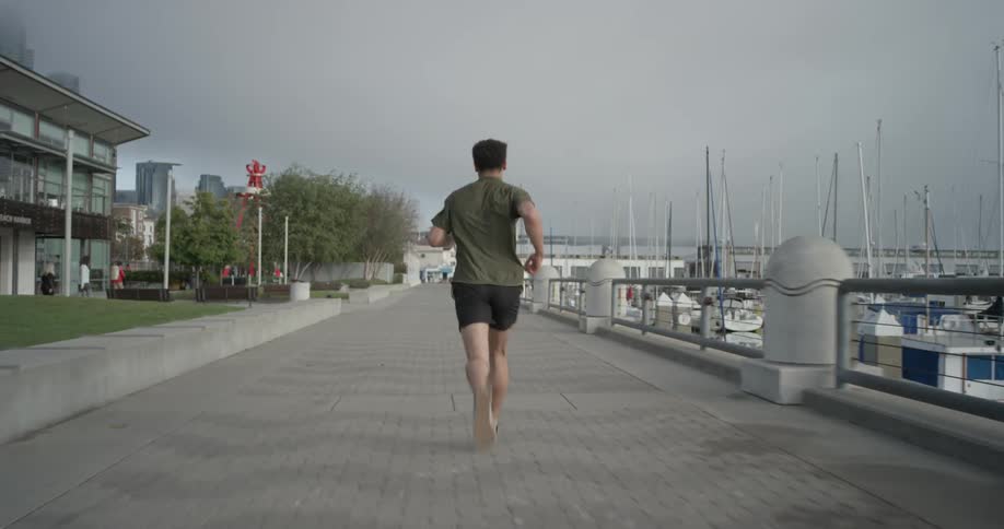 A man jogging down a pathway beside a marina