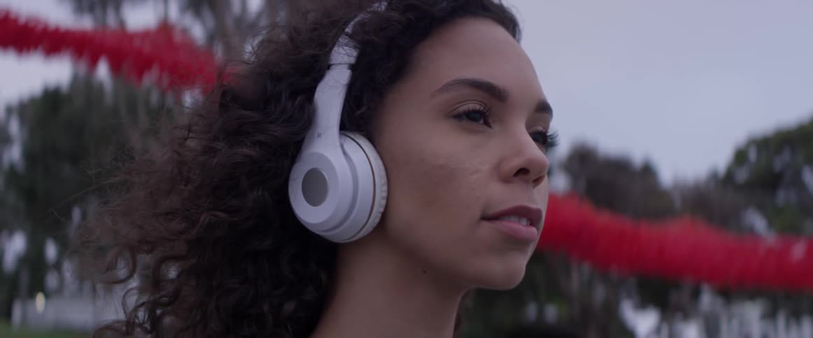 Woman listens to headphones outdoors