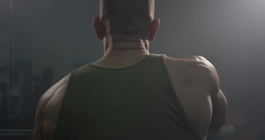 A man is exercising in a gym pulling ropes