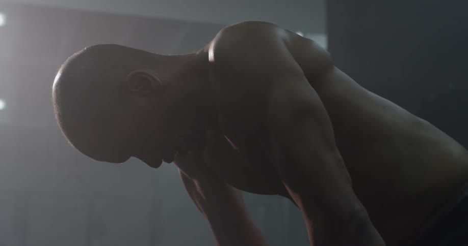 Man bent over breathing heavily in a gym