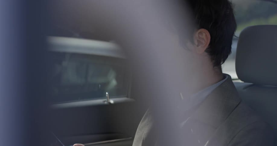 A man sits in a car working on his smartphone