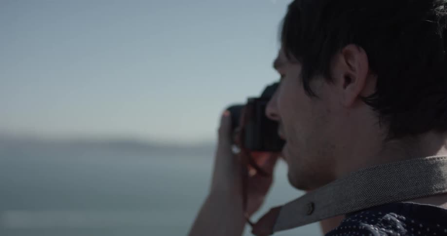 A man photographs a city laying on the opposite side of a body of water