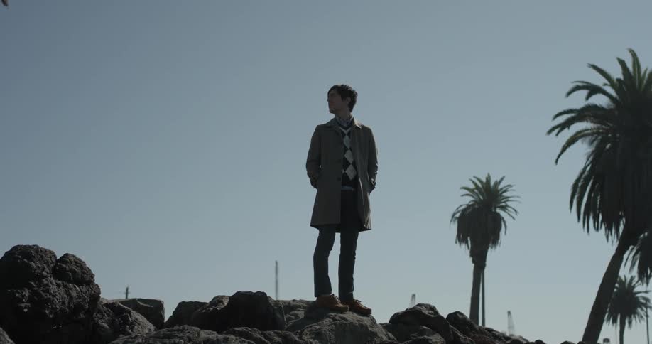 A man stands on rocks in the desert under a clear  blue sky