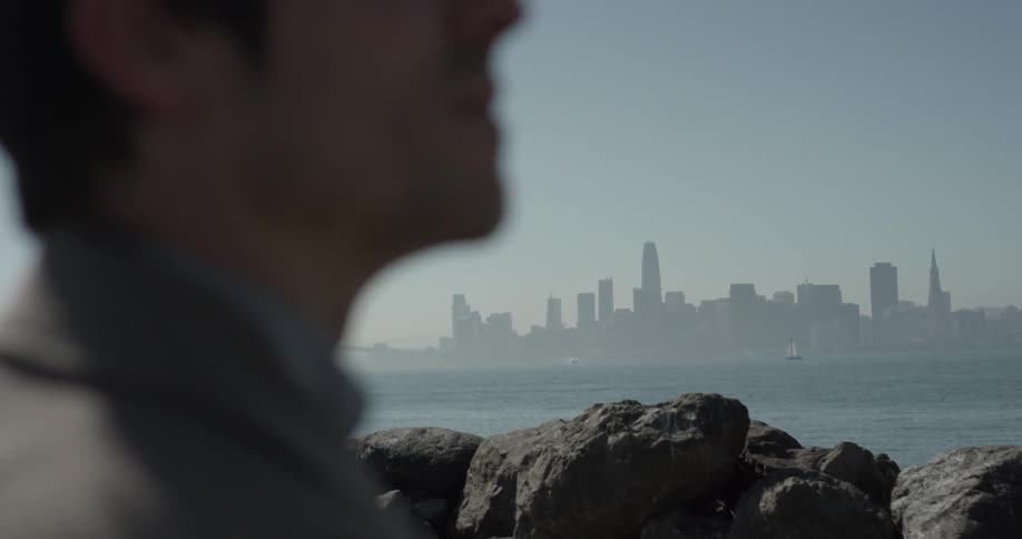 Man looking at a city across a bay