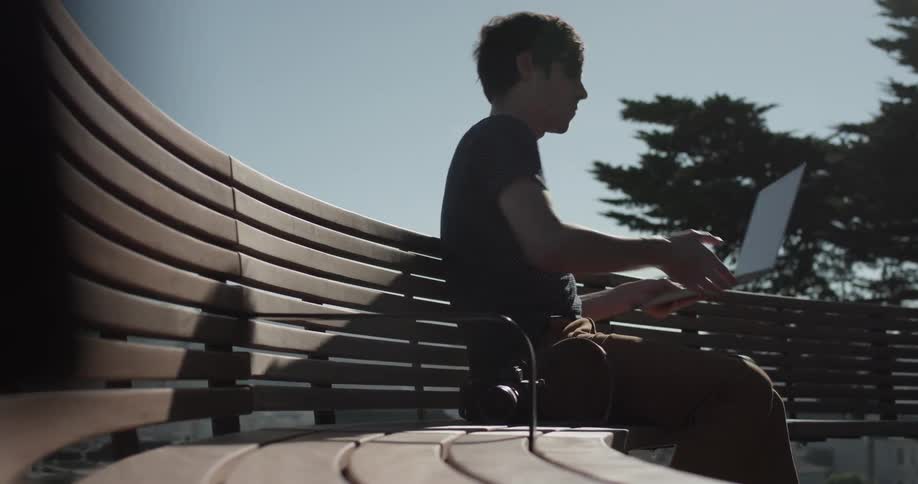 A man setting down a camera on a bench