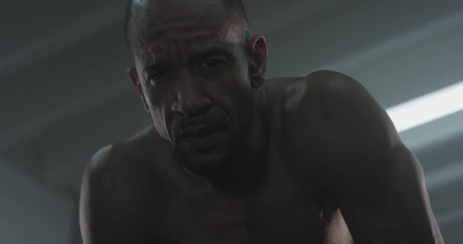 A man with no shirt looking up while breathing heavily