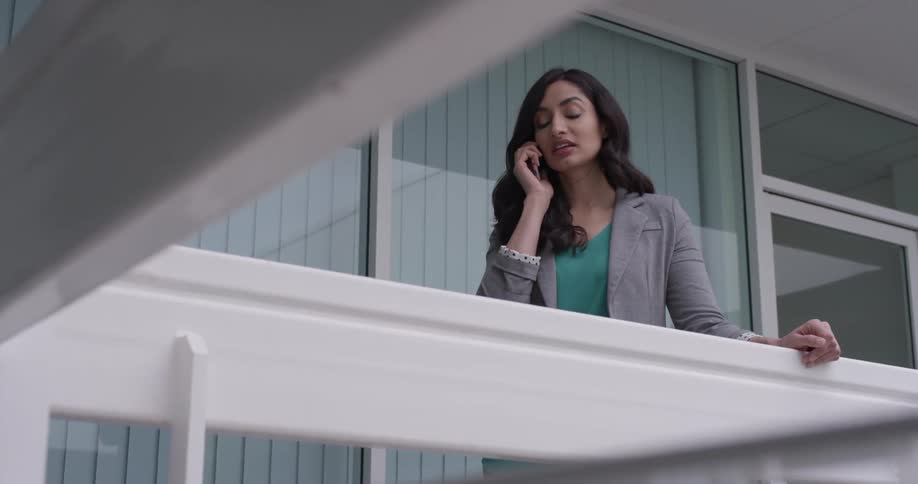 A woman standing on a balcony on her cell phone