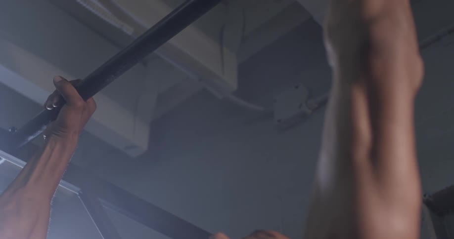 A muscular man does pull ups on a bar