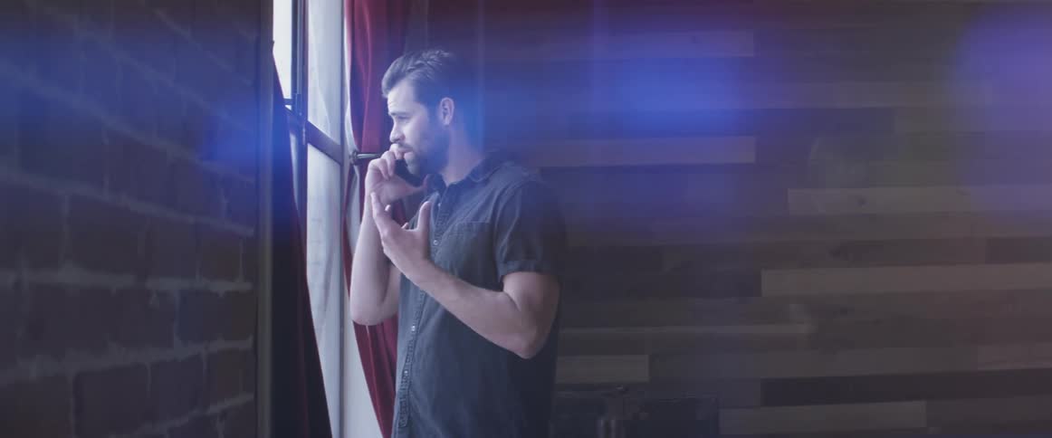 A man talking on a cell phone near a window