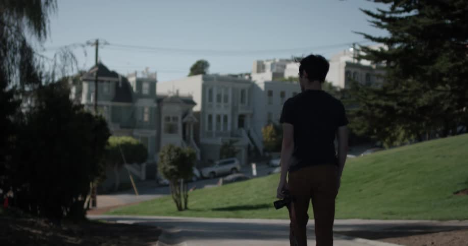 A man is walking outside while holding a camera