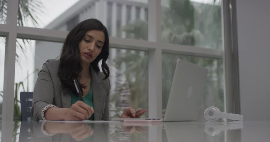 A woman writing down notes from her computer