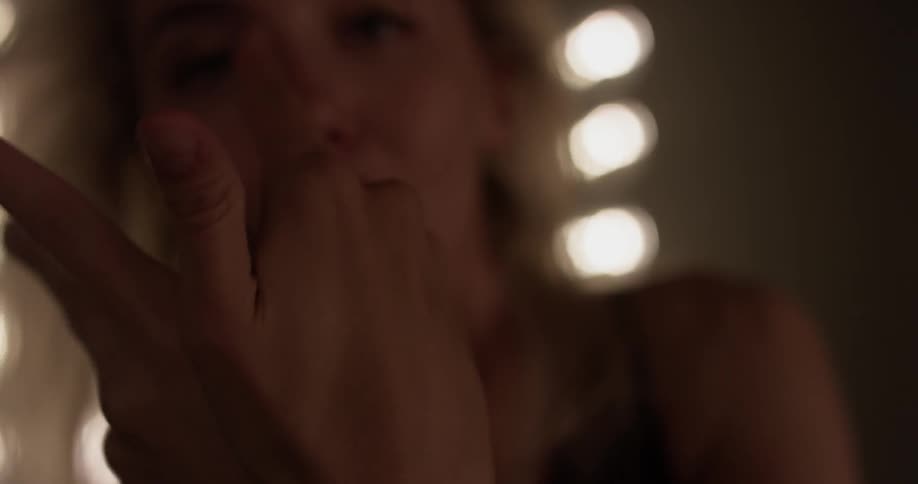 A close up of a blond woman dancing with her arms and head
