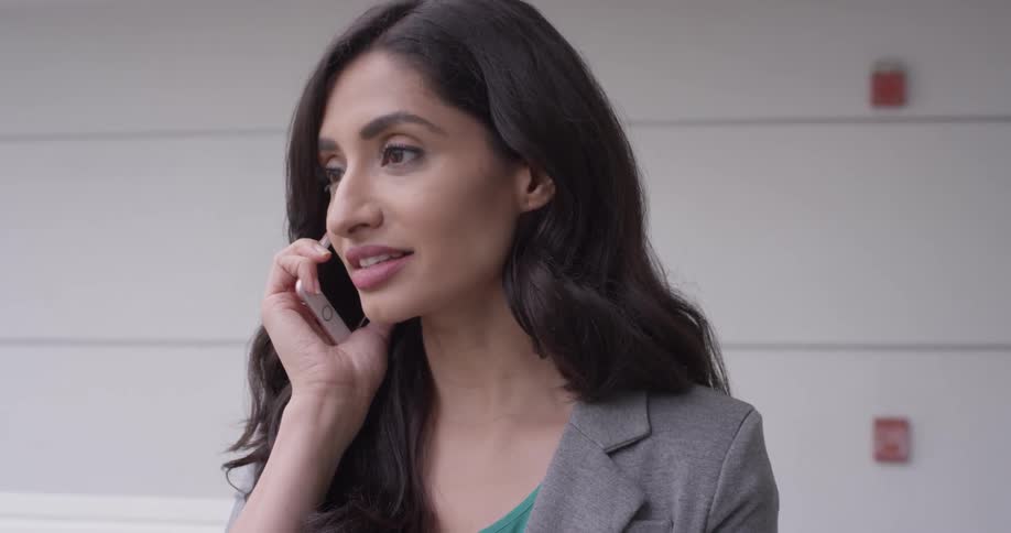 A woman nods her head and laughs while talking on the phone