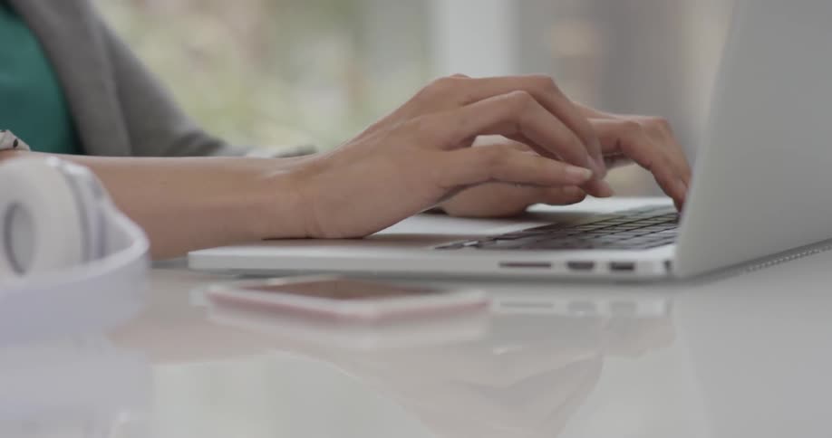 A woman's hands are typing on a laptop