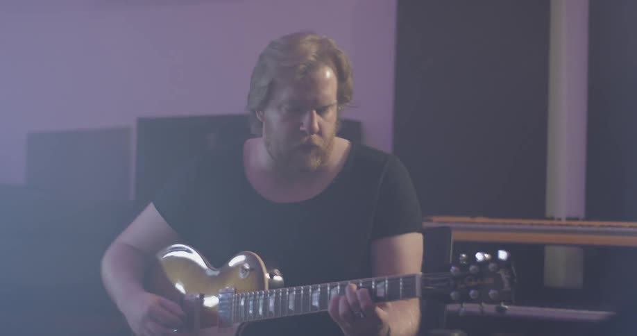 A man playing guitar in a studio