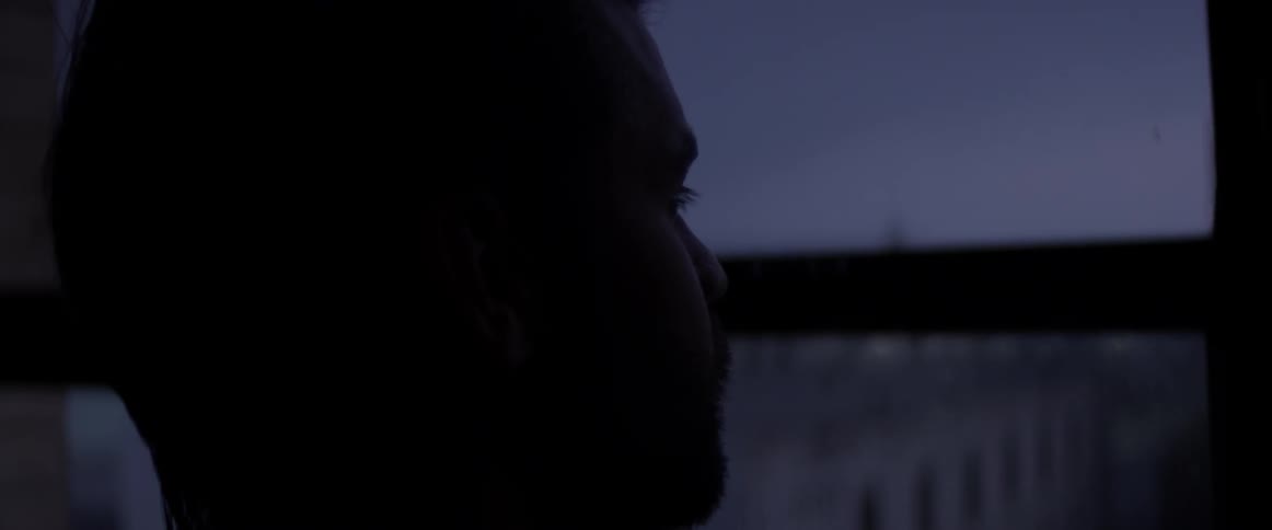 A man looking out a window at night