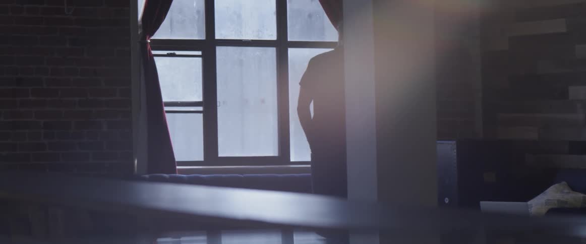 A person looking out a window while talking on a phone
