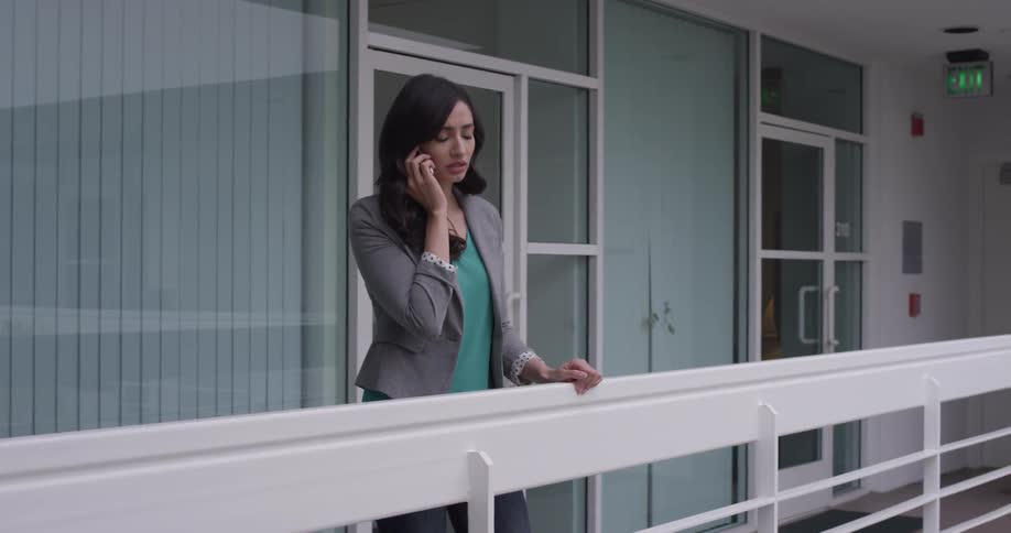 A woman standing on a balcony talking on a cell phone