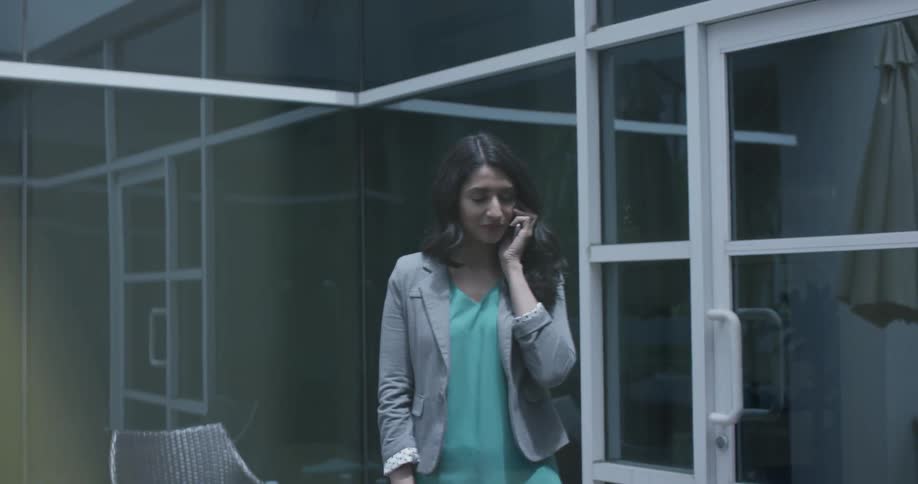 Woman stands in an office smiling and talking on the phone