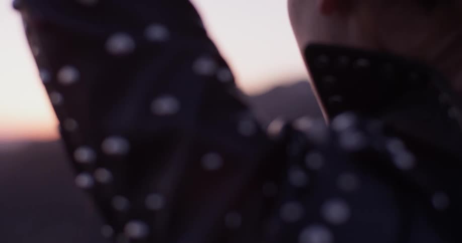 A woman moves her hair from off of her shoulder