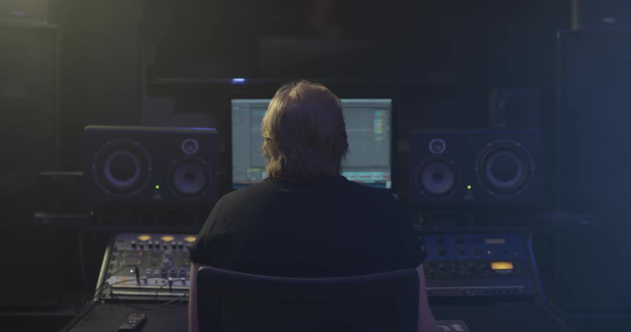 A man sitting in a studio mixing audio