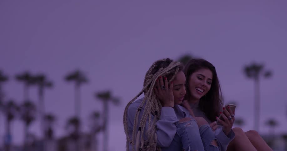 Two women laughing while looking at a phone