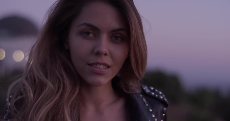 Woman stands outside at sunset