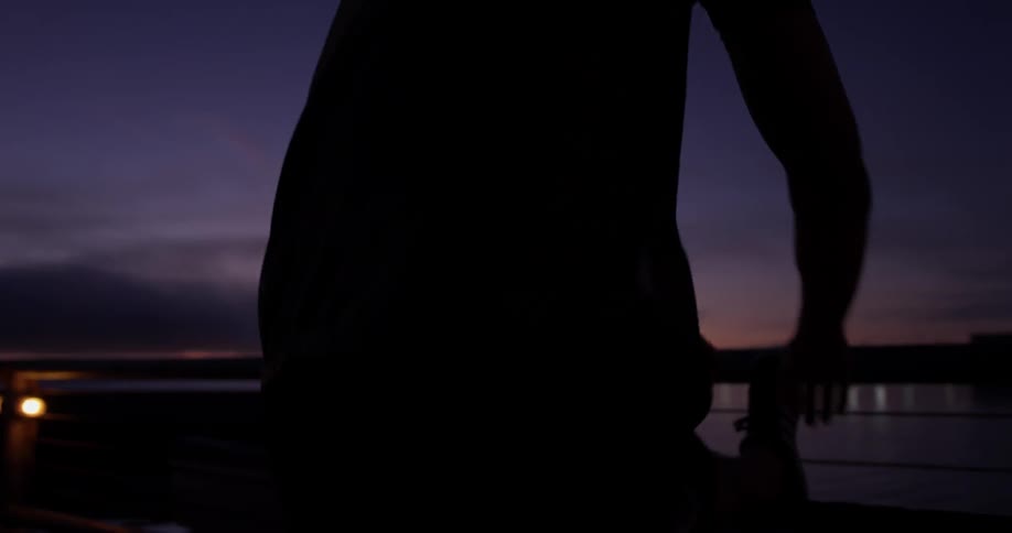 A man stretching on a wall at dusk