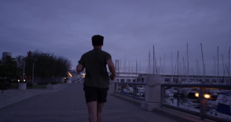 A man runs along a deck near a marina