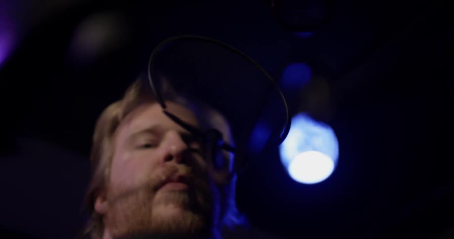 A man singing into a microphone in a studio