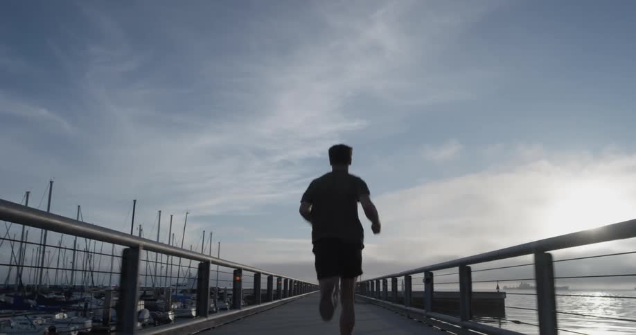 Man jogs on a bridge near the water