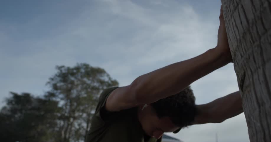 A man stretching against a tree