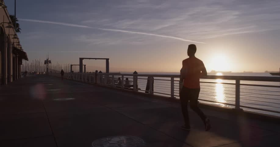 Man running along a pier at sunrise