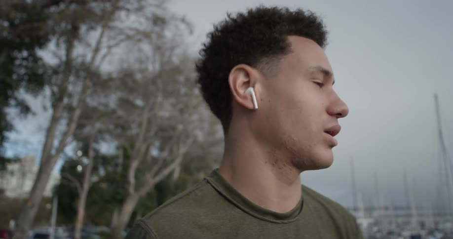 A man putting in headphones on a sidewalk
