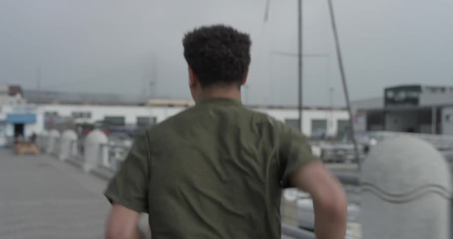 A man running down a pier next to some boats