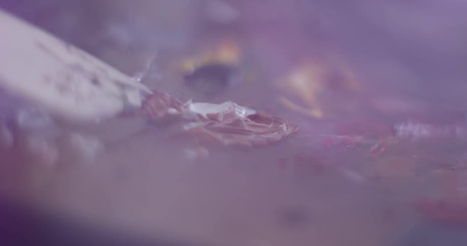 Paint brush dabs paint off a board