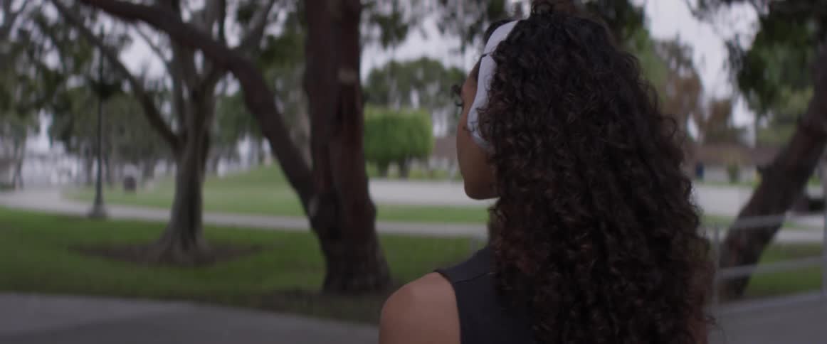 A woman walking down a sidewalk with headphones on