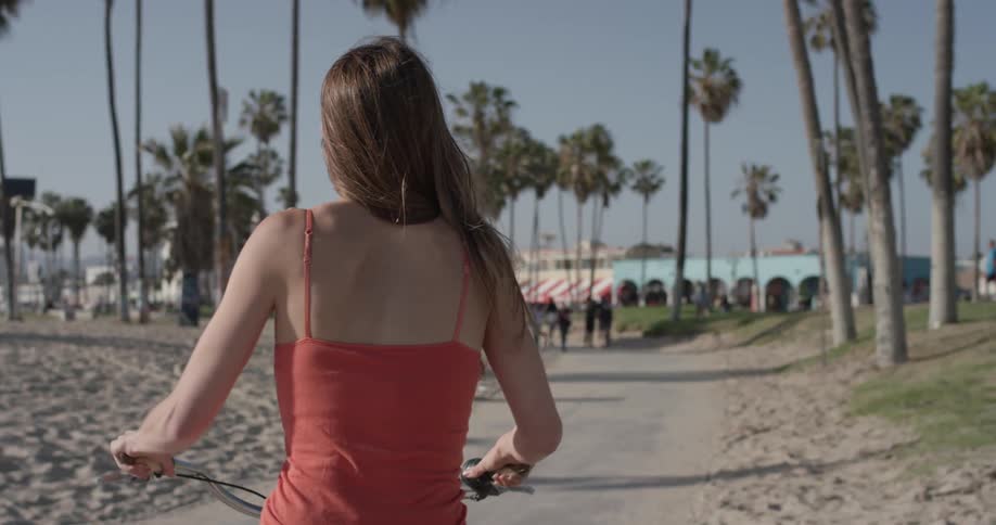 Woman rides her bike on the beach on a sunny day