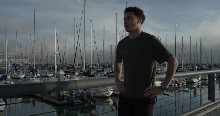 A man walking down a sidewalk next to some boats