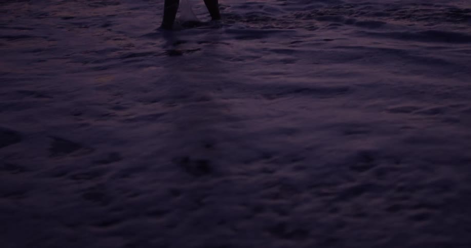 Person splashes through the water at sunset