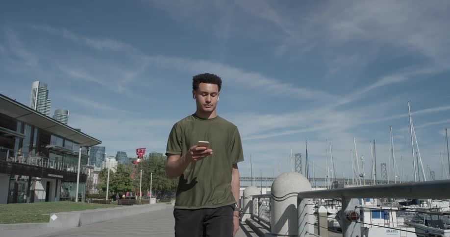 A man walking down a sidewalk carrying a phone