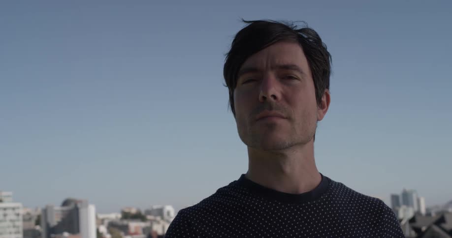 Man stands looking out with a city behind him