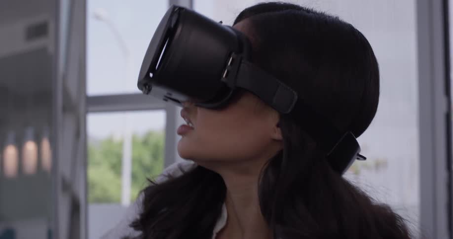 A woman flinched as she is scared by things in a virtual world she sees through the vr goggles she is wearing