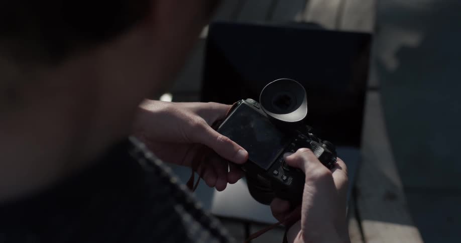 Man looks down at camera in his hands