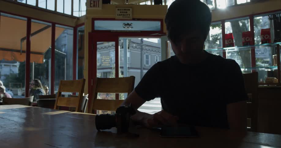 A person sitting a table using their cell phone