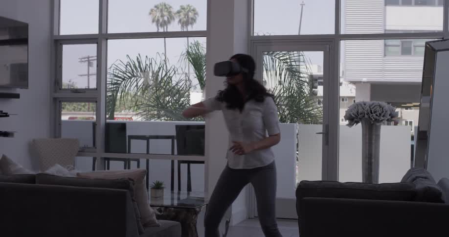 A woman is seen with virtual reality goggles on and seems to be playing a video game