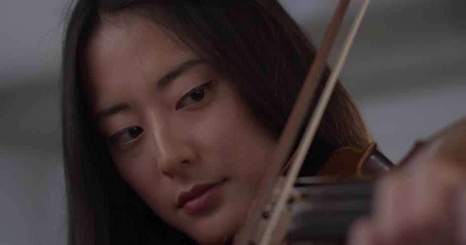 A woman plays a violin as her head bobs back and forth